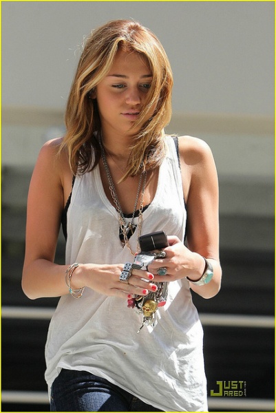 Miley Cyrus wearing a bra revealing top and skinny jeans
